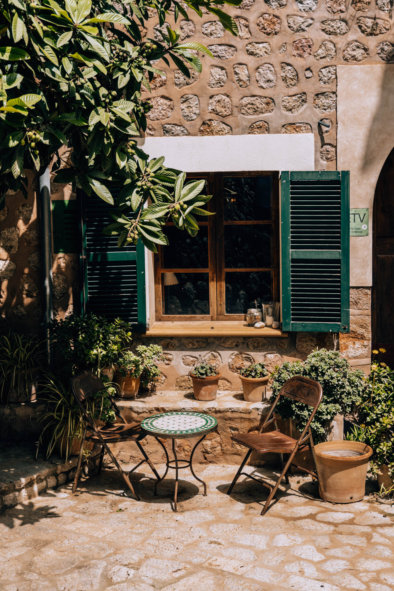Zielona okiennica i stolik z krzesłami w Fornalutx | Atrakcje na Majorce